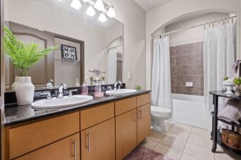 A bathroom with two sinks and a toilet and a shower